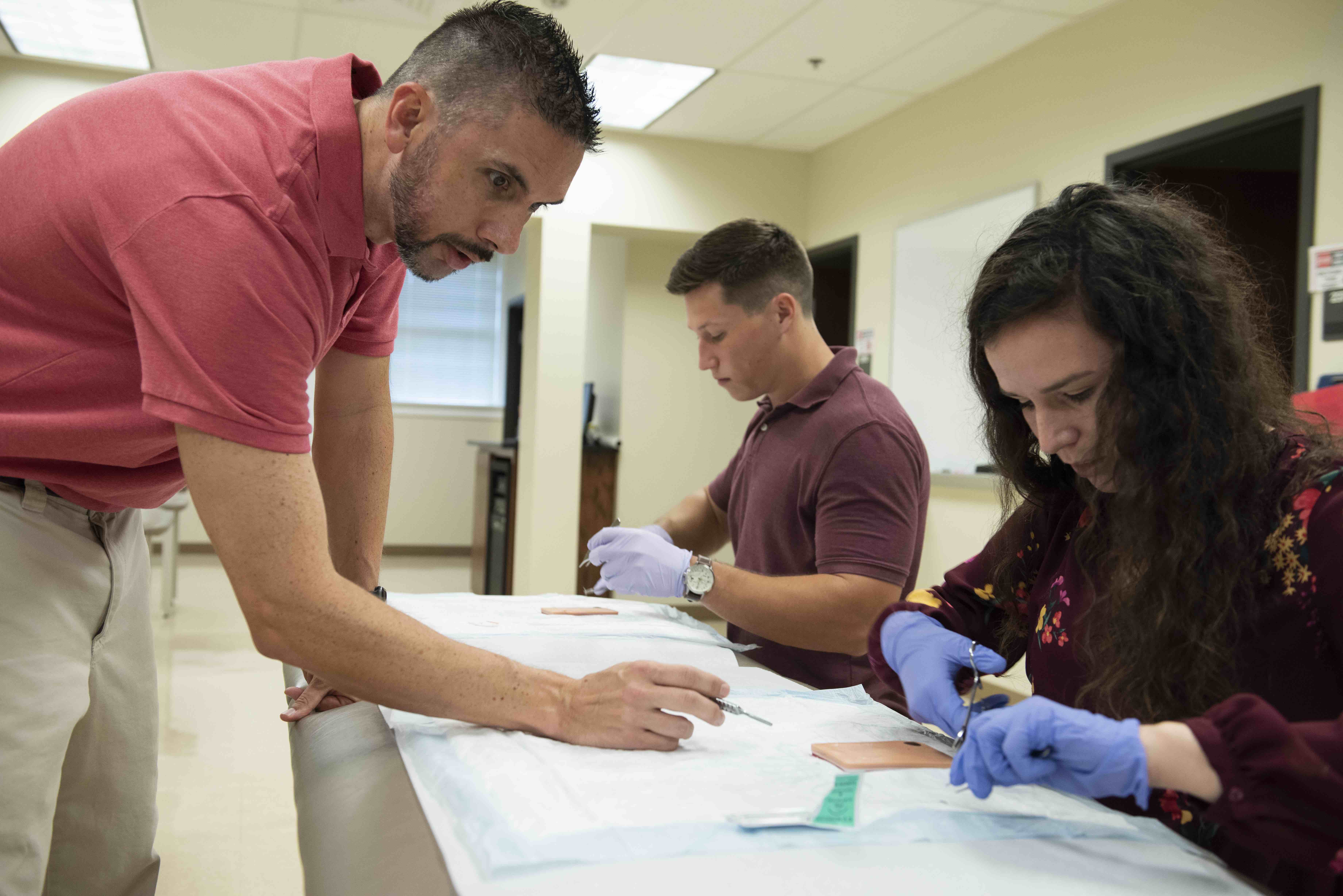 Assistant Professor of Physician Assistant Studies Shaun Lynch works with students on suturing procedure.