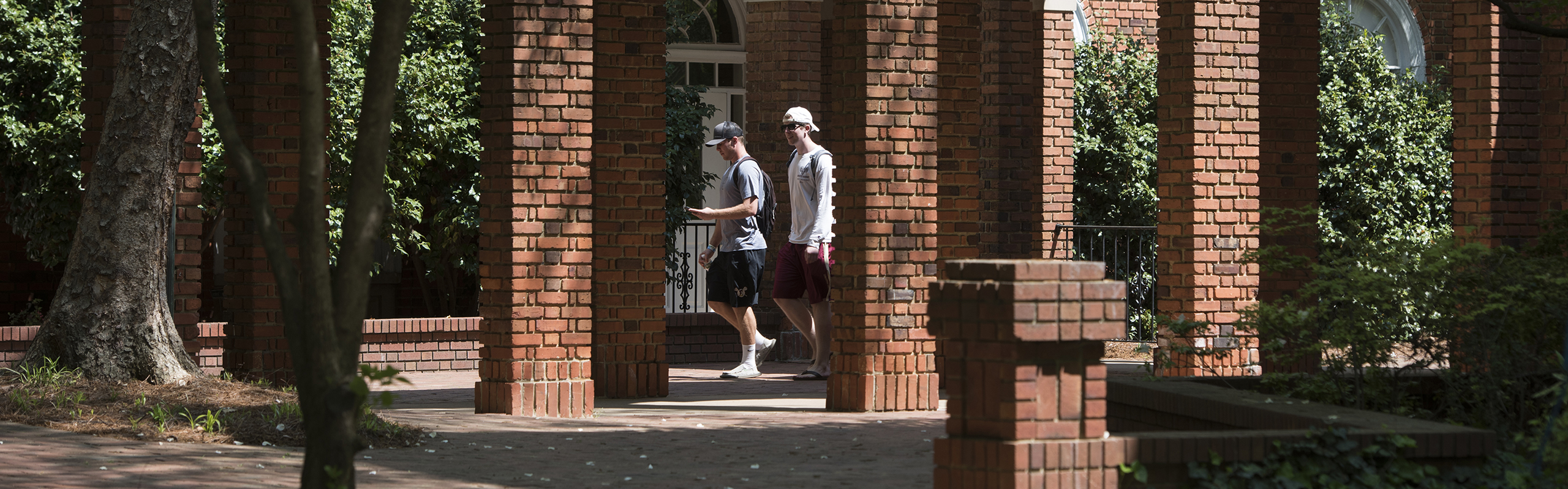 Two students walk around Elon's campus in the Spring.
