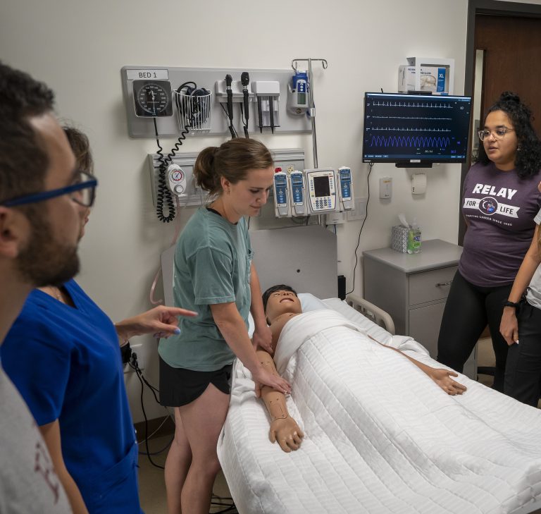 PA student Caroline Mea evaluates a mannequin during a patient simulation as classmate Rachel Alexander observes.
