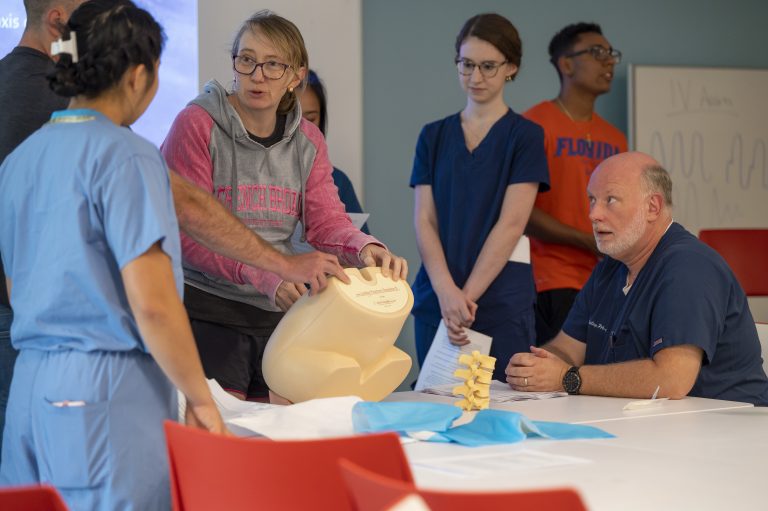 Associate Professor of Physician Assistant Studies Russ Dailey observes PA student Sarah Daley during a lab with mannequins.