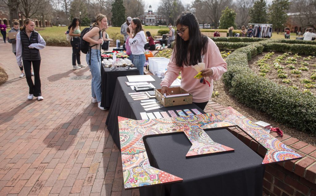 Shriya Baru ’25 arranges the handmade bookmarks she offers for sale at the Marketplace Under the Oaks Pop-Up Shops at Young Commons Thursday, February 17, 2022. Baru said the large hand-painted letter “E” on display is not for sale; she had too much time and effort into it that she didn’t want to part with it. (Rob Brown photo)