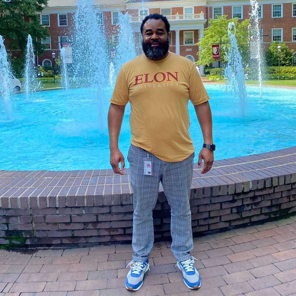 Elon M.Ed alum Issac Marsh standing in front of the Alamance fountain on Elon's campus.