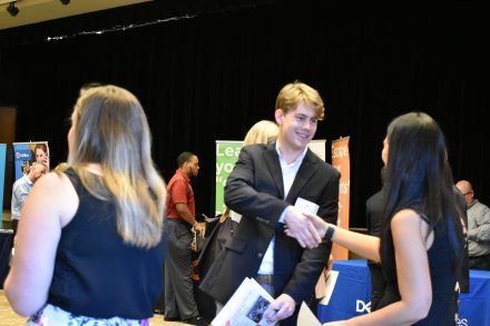 Student shakes hand with a recruiter at career fair.