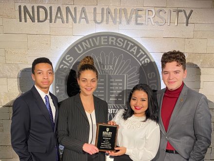 Four students standing holding an award plaque.