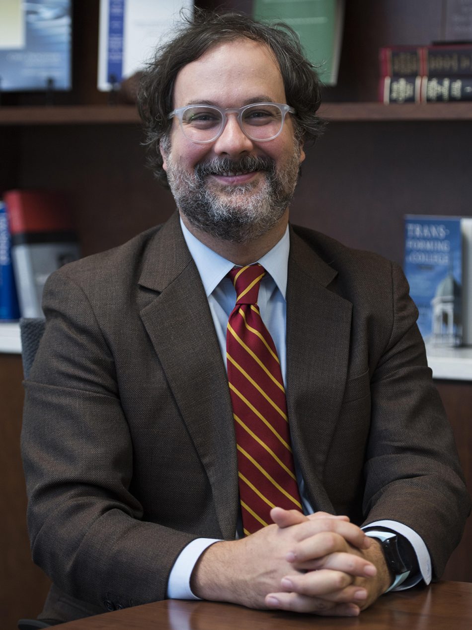 Picture of a man in suit and tie in front of a bookcase