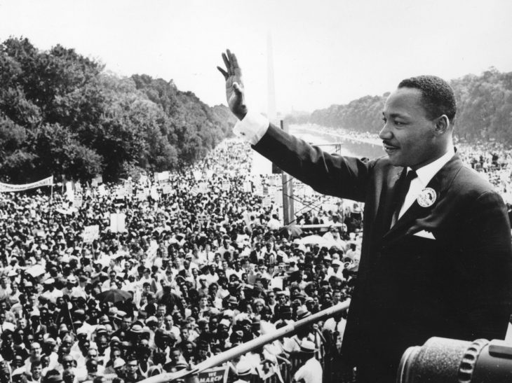 Martin Luther King Jr. puts his hand up and waves during the March on Washington. Photo is in black and white