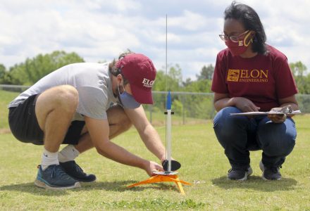 Andrew Jackson '21 werkt samen met universitair hoofddocent Sirena Hargrove-Leak om de 3D-geprinte raket van zijn team voor te bereiden voor lancering op het oefenveld van de zuidelijke campus.