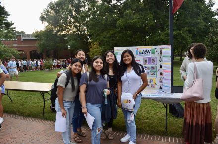 Five Latinx/Hispanic students smiling in front of the table of the Latinx-Hispanic Federation at the Student Organization Fair. 