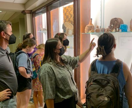 Students examine works of art in a display case.
