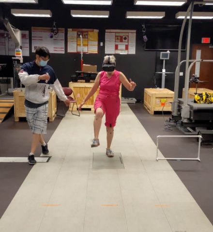 A user wears a virtual reality headset while walking with an assistant and testing the VR-based physical therapy application that examines how people navigate obstacles.