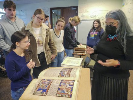 A professor discusses a collection of facsimiles arranged on desks in a Lindner Hall classroom.