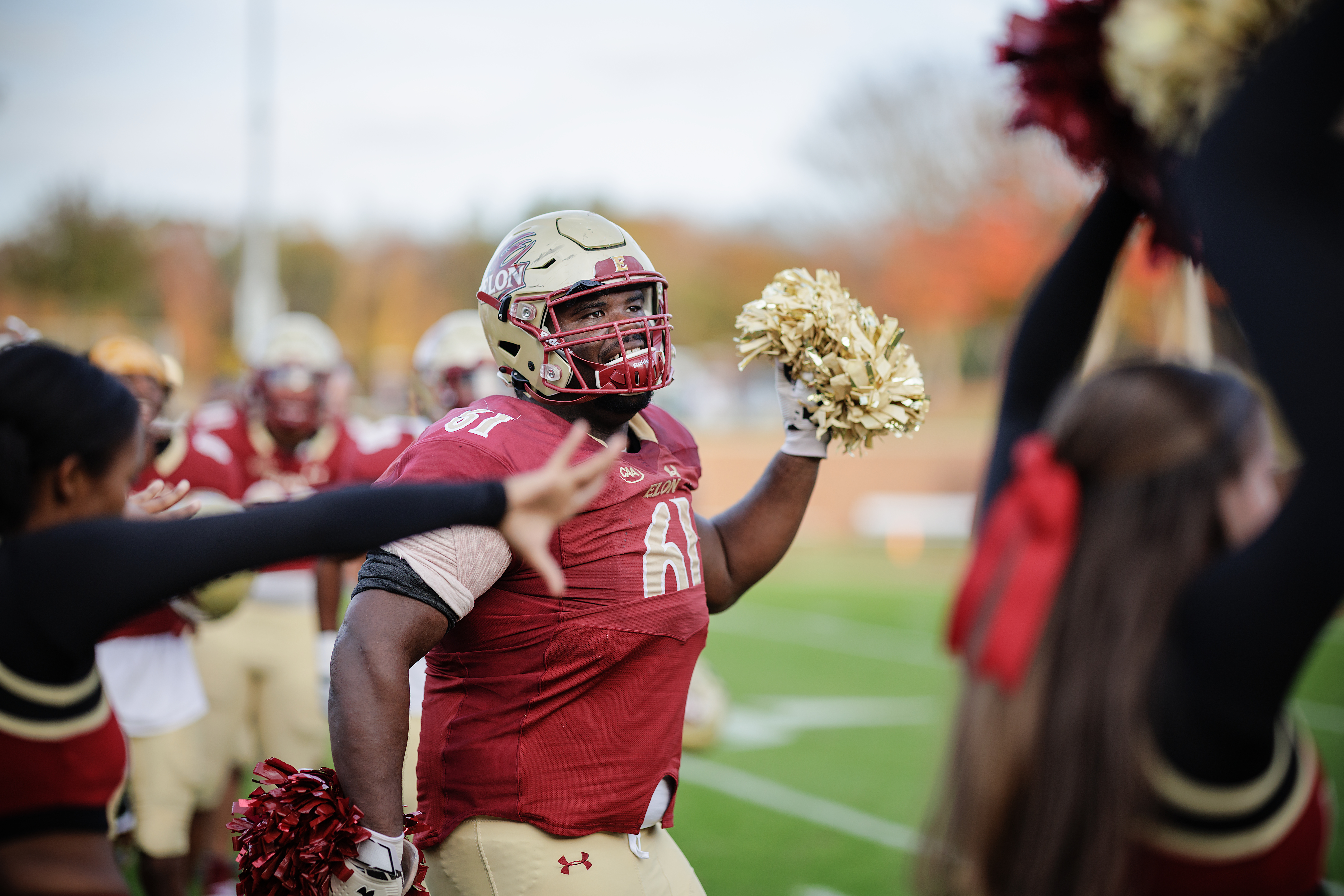 Elon football player celebrating with pom poms during the Albany game. 
