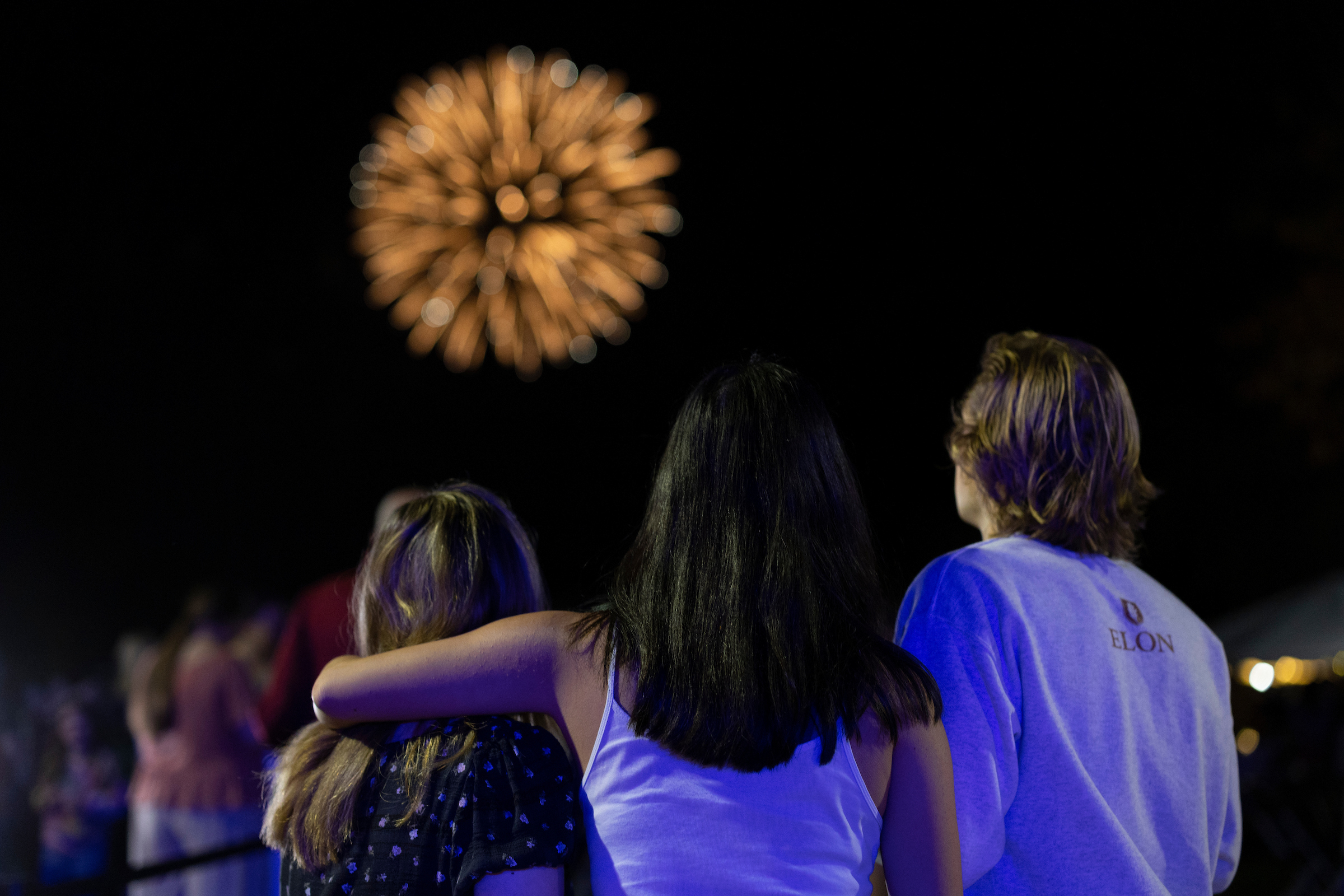 Three students gazing at fireworks. 
