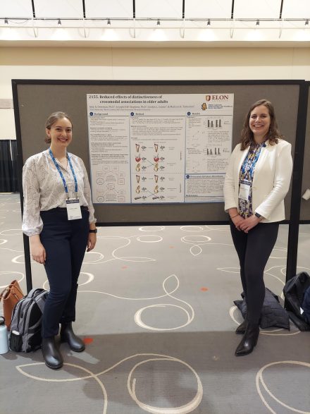 two women standing next to a research poster presentation