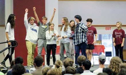 A group of students onstage cheering with a trophy