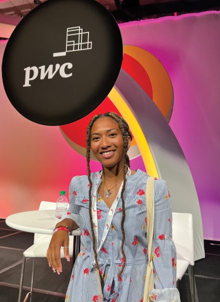 Elon University student Mari’ Robinson ’24 poses in front of the pwc logo during one of her internships