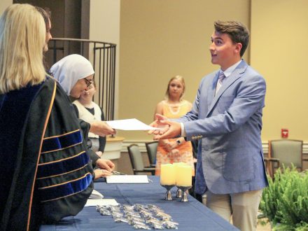 An undergraduate gets a pin and certificate.