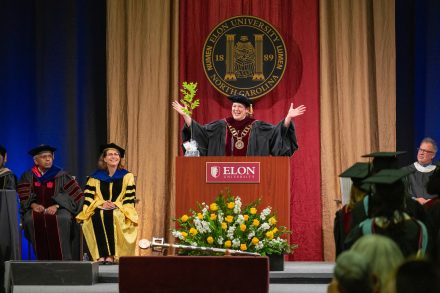 Elon President Connie Ledoux Book stands behind the podium on the Commencement stage with an oak sapling in her hand