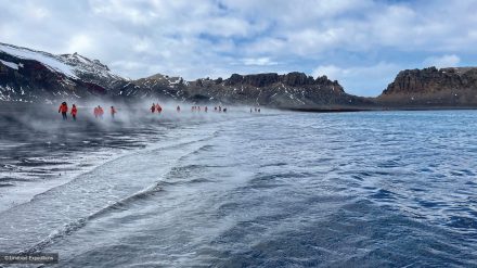 The expedition group walks along the steaming active volcanic beach at Deception Island in the Antarctic Peninsula. 