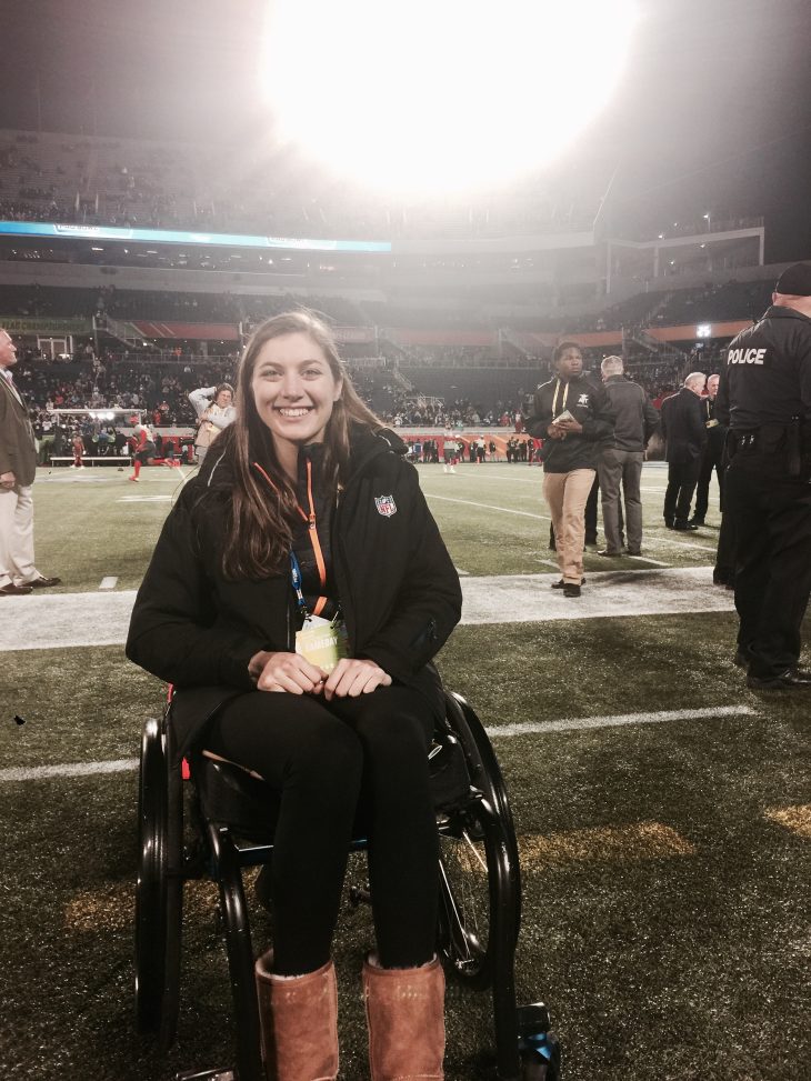 Avery '16 poses for a photo on the field at an NFL game.