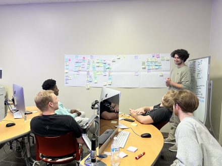 John Spitznagel '23 at a white board in front of a group of four students