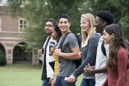 Five students walking on a college campus