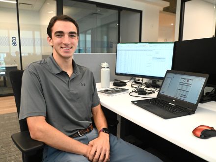 A white male student sits at a computer work station.