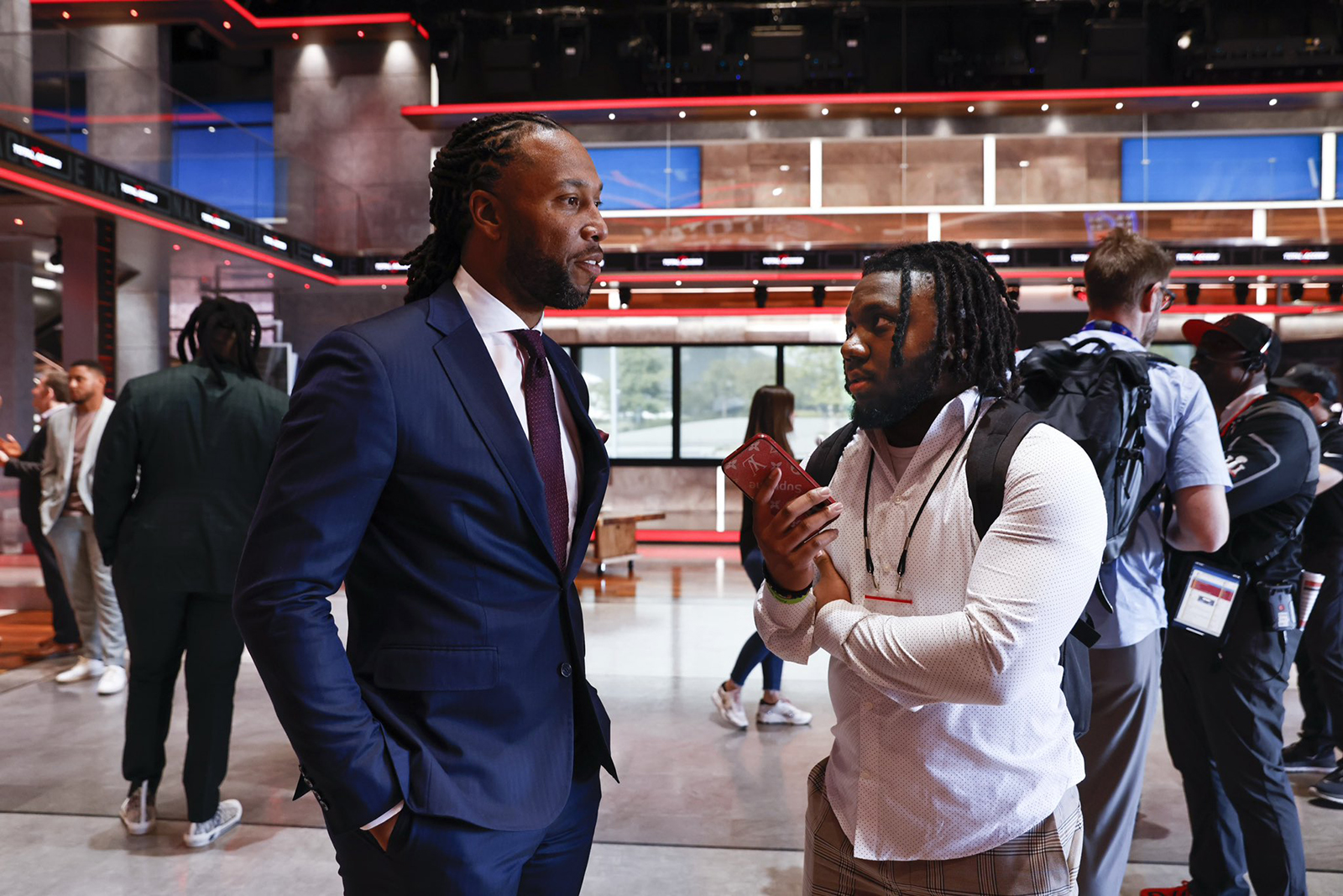 Two Black men stand together during an interview. Pictured left is NFL legend Larry Fitzgerald and Elon alumnus Emmanuel Morgan.