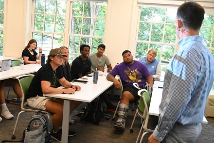 A group of student-athletes sit together in a university classroom.