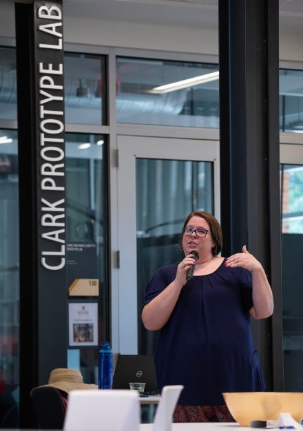Kim Stokes with a microphone in front of the Clark Prototype Lab