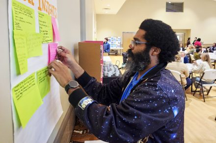 a man putting post-it notes on a board