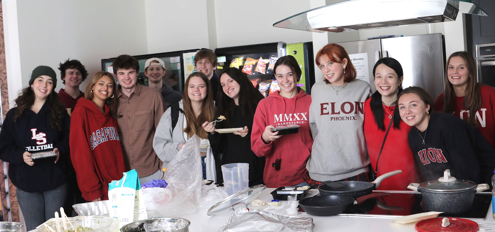 A group of 12 students gather in a line in front of a stove top.