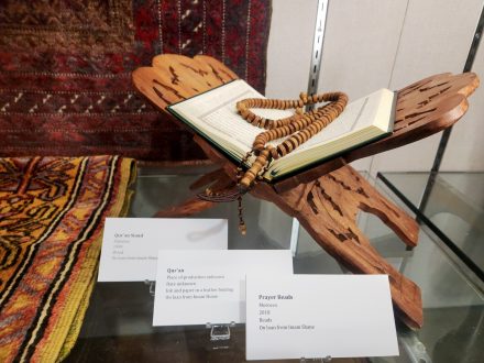 Prayer beads and a Qur'an rest on an ornate wooden stand