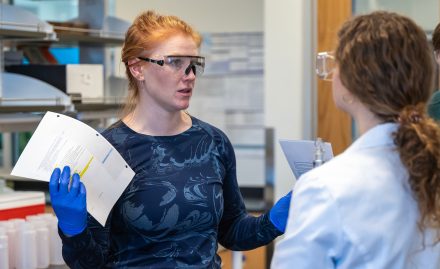 Julia Darcy in lab attire with students