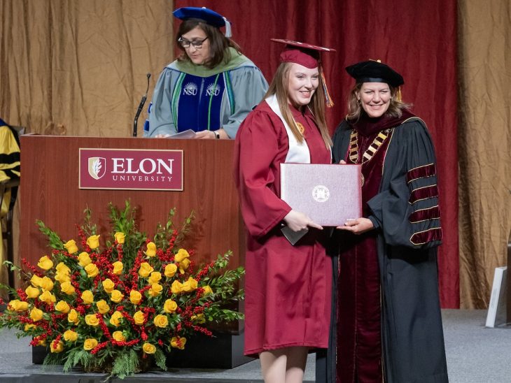 ABSN program graduate Taylor Mellow '23 receives her diploma from President Connie Ledoux Book at commencement in December 2023 as Dean Maha Lund, rear, recognizes members of the graduating class.