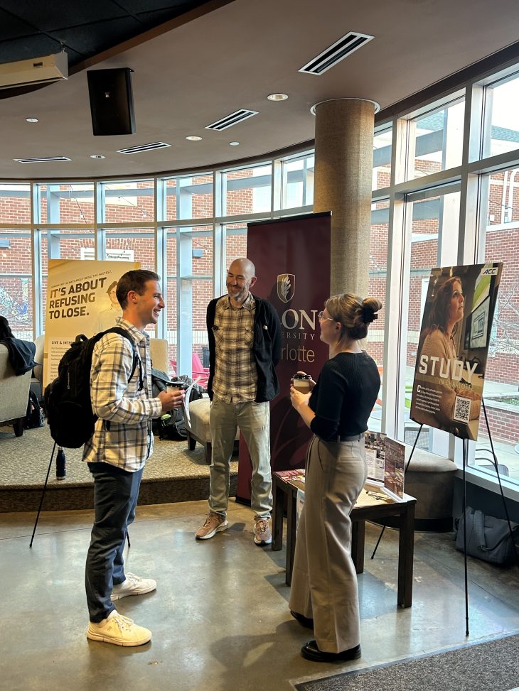 A student talking with Elon faculty and staff at an informational session. 