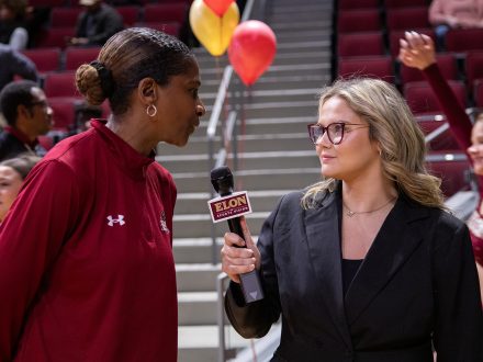 A female student holds up an Elon Sports Vision mic to record an interview.