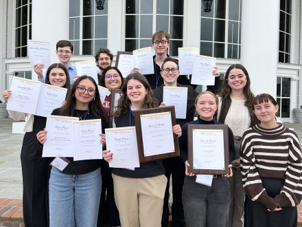 Elon students hold up awards while attending NC College Media Association conference.