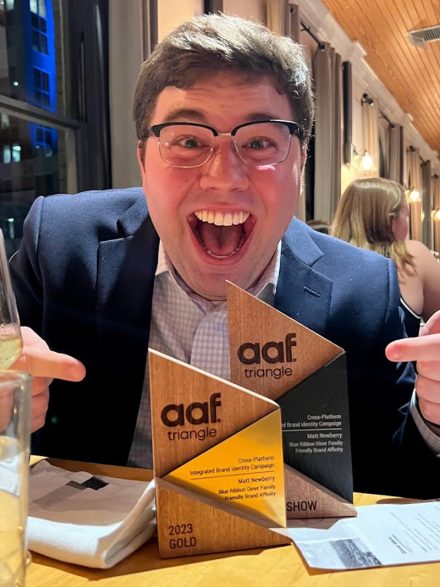 Matt Newberry stands with a huge smile and two ADDY awards.