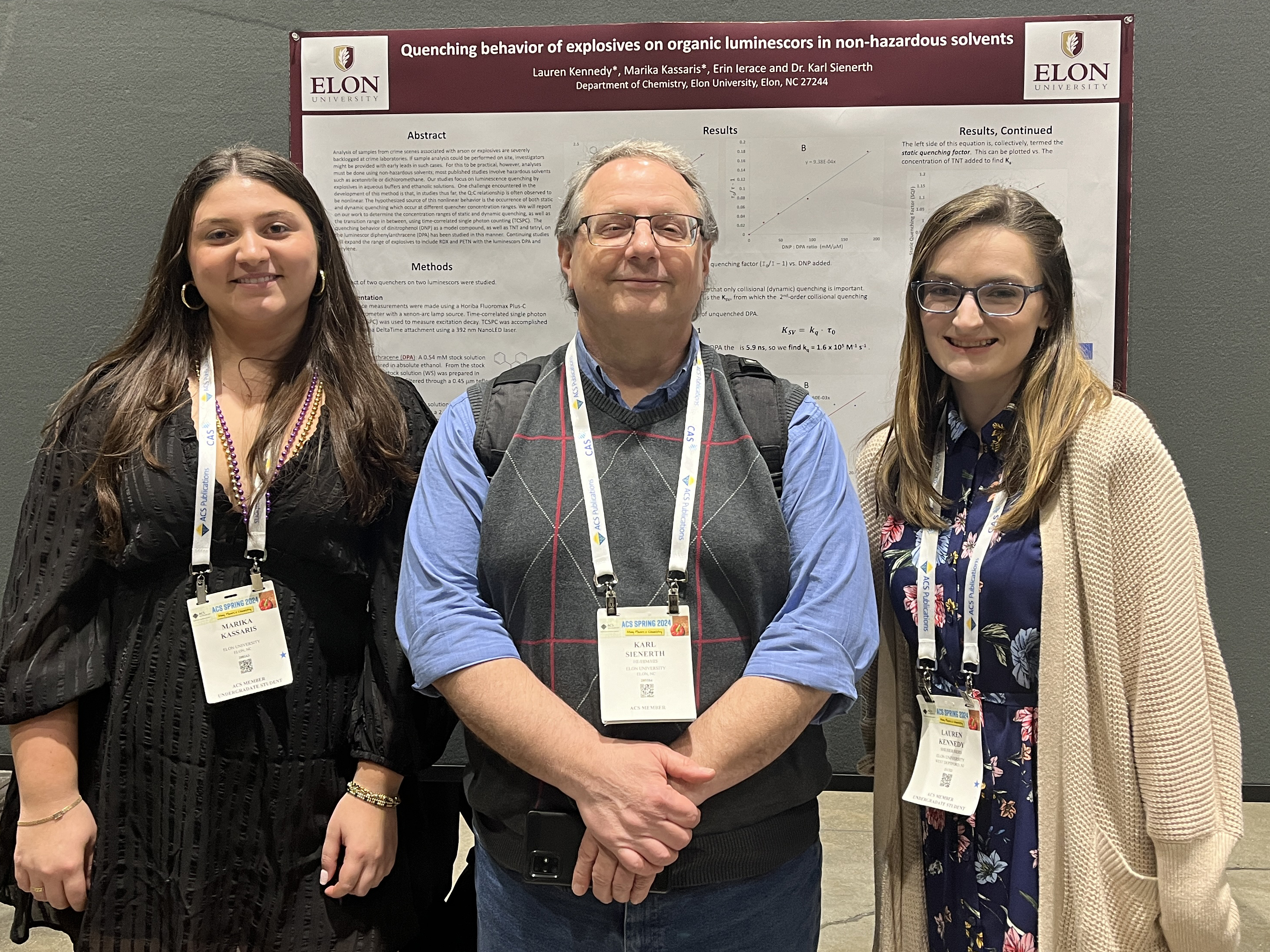 Two female students and a male professor with a research poster