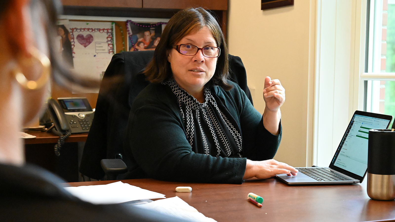 Vanessa Bravo sits at her desk in Schar Hall at Elon University.