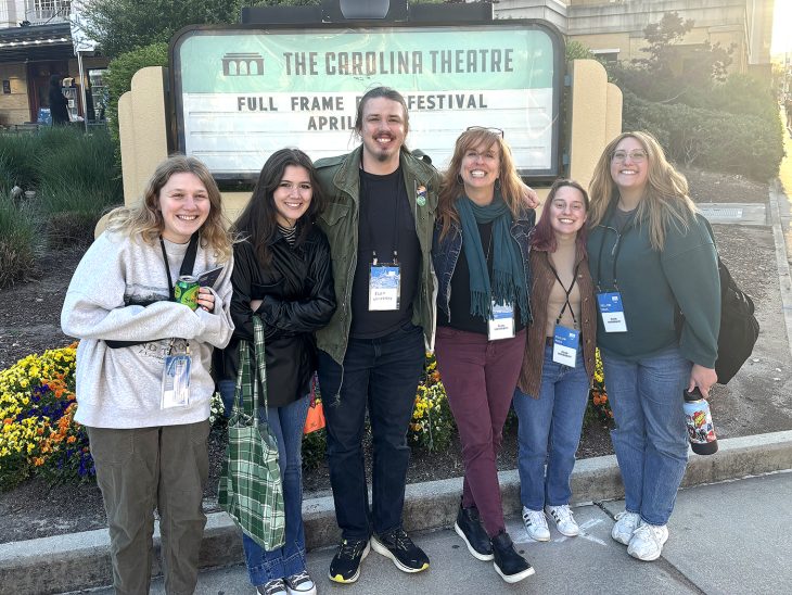 Elon film students stand in front of Carolina Theatre sign in Durham, North Carolina.