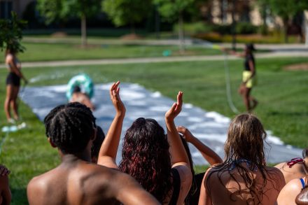 Students cheer on others as they go down a slip and slide. 