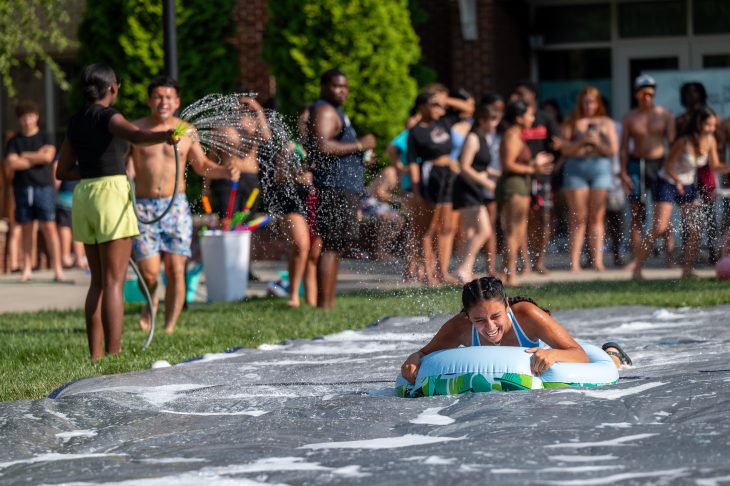 Person slides down slip and slide with crowd watching