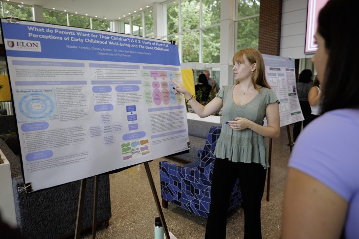 Natalie Peeples points to poster board presentation