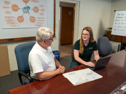 Two people sit at a conference table