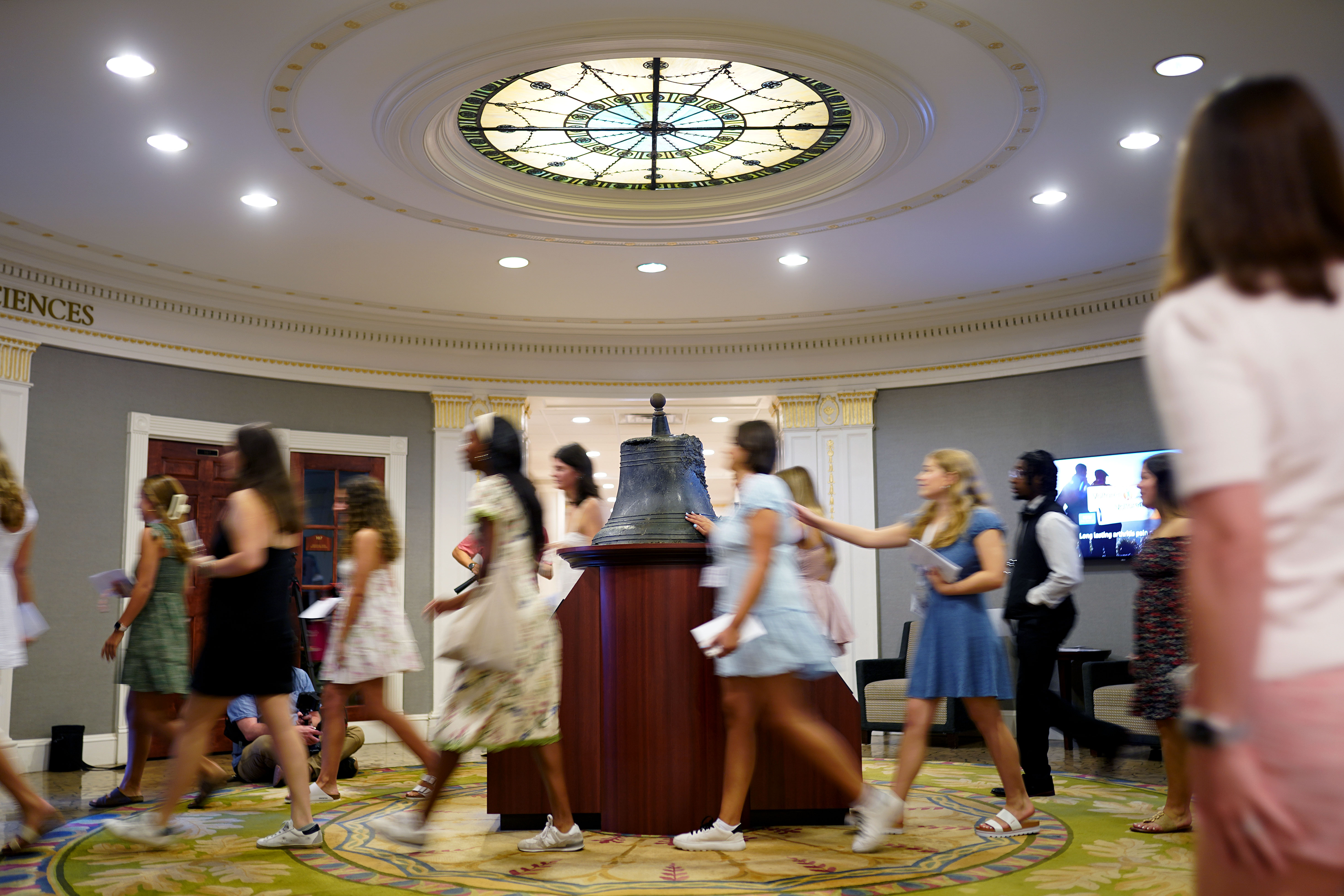 A line of students touches the bell in Alamance building