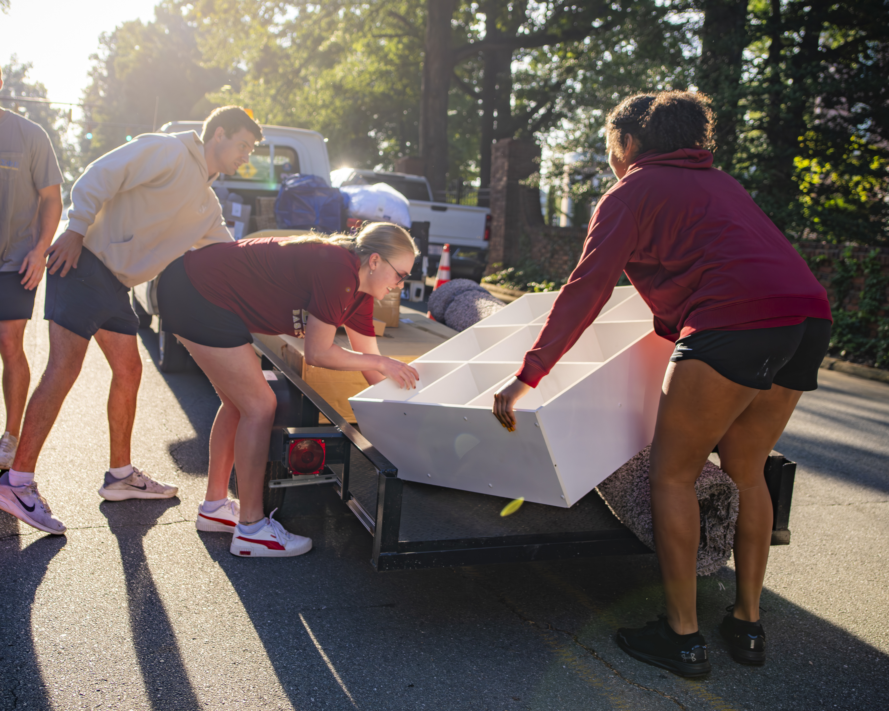 Several people lift a white shelf