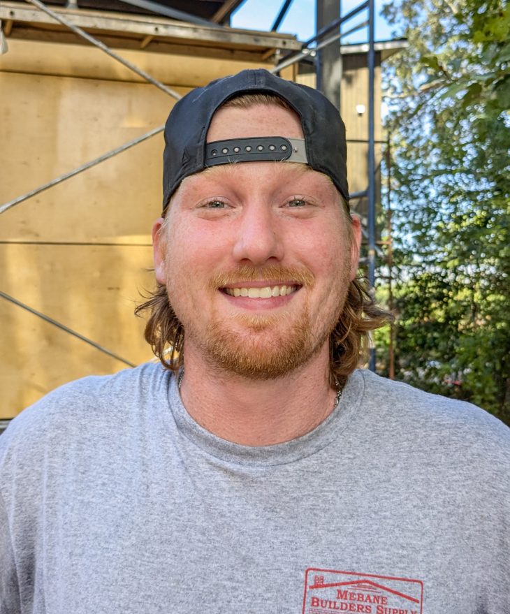 headshot of a man in a backwards ballcap at construction site