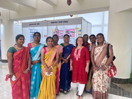 A group of women in colorful dresses in a university meeting space